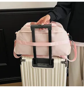 Pink lightweight travel duffel bag with trolley sleeve mounted on a white suitcase handle
