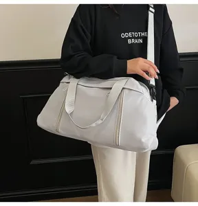 Side view of a large white travel duffel bag with shoulder strap shown in a lifestyle setting