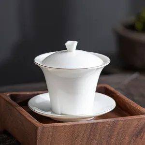 Elegant Dehua white porcelain gaiwan tea set with gold rim presented on a wooden tray