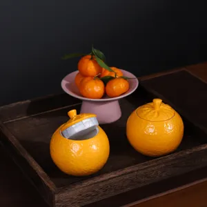 Boîtes à thé en céramique en forme d'orange sur un plateau en bois rustique