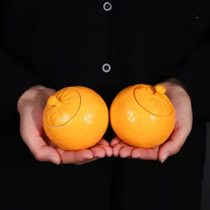 Deux boîtes à thé en céramique en forme d'orange pour un rangement portable.