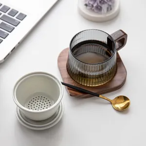 Modernes Glas-Teetassen-Set mit Holzgriff und Keramik-Sieb auf dem Büroschreibtisch