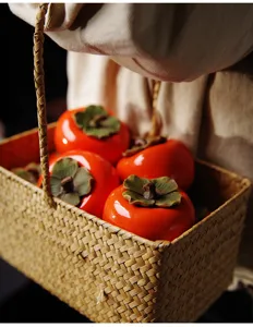 Détail de boîtes à thé en céramique orange en forme de persimmon dans un panier