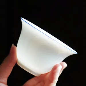Elegante tazza da tè in porcellana bianca Dehua con bordo blu, gaiwan Kung Fu tenuto in mano