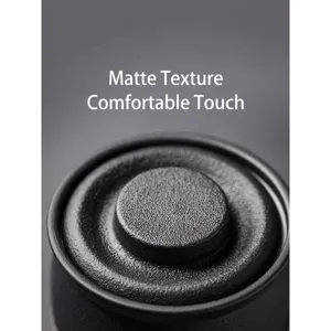 Macro view of a black matte ceramic mug lid showing detailed grainy texture and finish