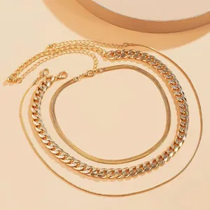 Close-up detail of punk style gold chunky curb chain and flat snake chain necklace set
