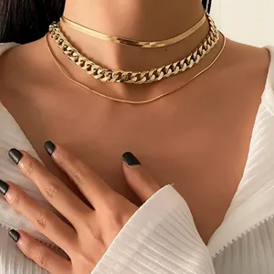 Close-up detail of a gold-tone chunky curb chain and layered snake bone necklace set