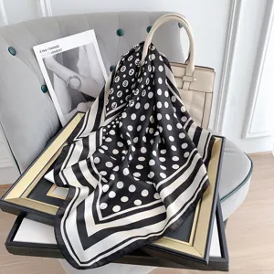 Foulard vintage in seta a pois e strisce bianche e nere su una borsa a mano beige di lusso.