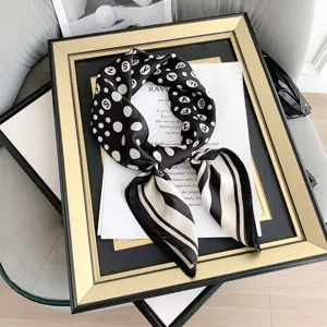Dettaglio ravvicinato di un foulard vintage in seta bianco e nero con pois e lettere