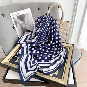 Elegante sciarpa di seta a pois blu scuro drappeggiata su cornice e borsa