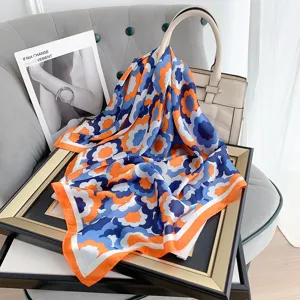 Dettaglio di un foulard quadrato in seta retrò a fiori arancio e blu