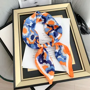 Dettaglio di un foulard in seta floreale retrò su una cornice vintage con pagina di libro.