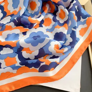 Dettaglio di un foulard di seta retrò con motivi a fiori arancioni e blu
