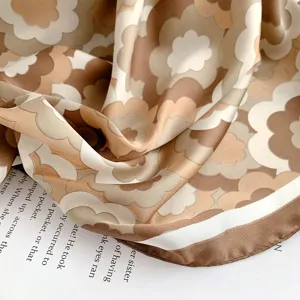 Dettaglio macro del motivo floreale retrò su un morbido foulard di seta marrone e beige