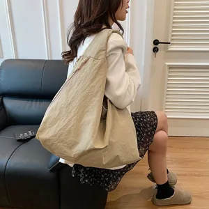 Detail der großen beigen Nylon-Hobo-Tasche, die von einem Model getragen wird.