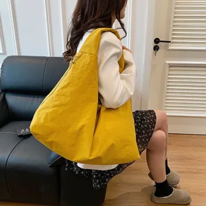Geräumige gelbe wasserfeste Nylon-Hobo-Tasche am Modell in einer lässigen Umgebung