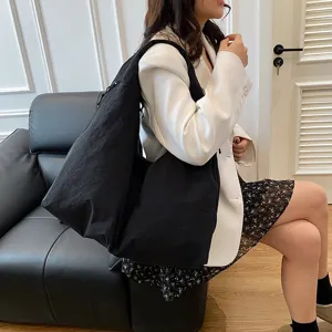 Große schwarze Nylon-Hobo-Tasche, von einem Modell in einer lässigen Umgebung getragen.