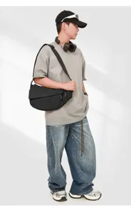Detail shot of a black geometric crossbody sling bag styled on a male model, modern streetwear.