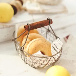 Close-up of vintage iron wire bread basket featuring a rustic wooden handle and warm tones