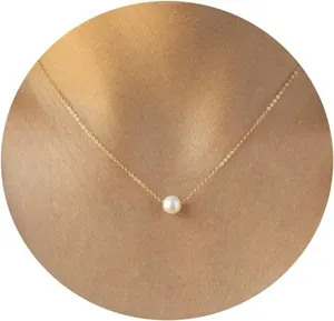 Close-up detail of an elegant gold necklace with a single white pearl pendant on neck.