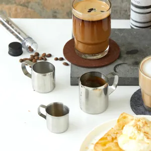 Detailansicht von drei Mini-Milchkännchen aus Edelstahl für Kaffee, Sahne und Sirup