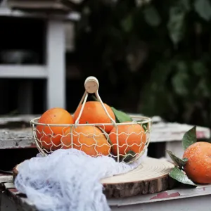 Rustic cream wire fruit basket with oranges on a decorative wood slice base