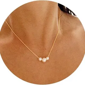 Elegant gold chain necklace with three pearls worn by a model in a minimalist style