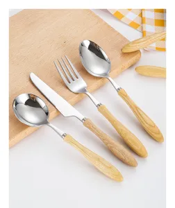 Set of 4 stainless steel cutlery pieces with natural ash wood handles on cutting board.