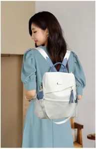Fashionable cream and blue anti-theft backpack for women, styled by model in a casual setting.