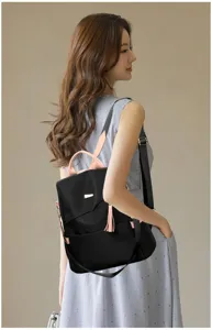 Black anti-theft backpack for women featuring stylish pink straps and tassel on a lifestyle model