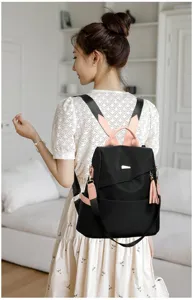 Back view of a black women's anti-theft backpack with pink straps and tassel detail.