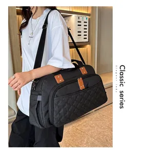 Vue détaillée du grand sac de voyage noir matelassé avec texture et détails en cuir marron.