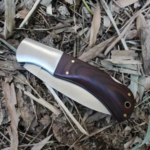 Close-up of a folding camping knife featuring a steel bolster and dark wood handle