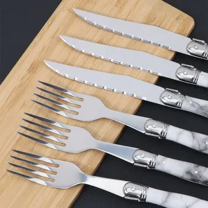 Stainless steel steak knife and fork set with marble pattern plastic handles for kitchen use.