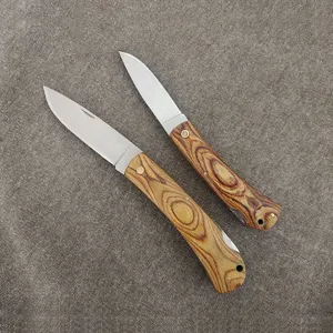 Macro view of sharp folding pocket knives with textured wooden handles on grey fabric
