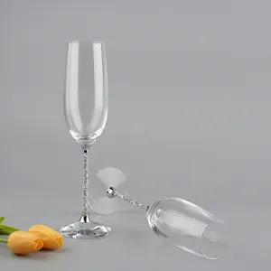 Par de elegantes copas de champán de cristal con tallos llenos de diamantes brillantes.