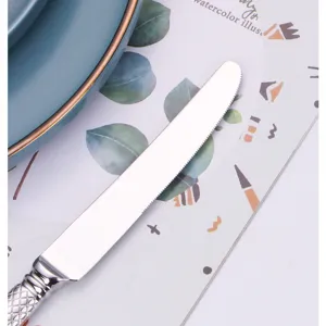 Primo piano di un coltello in acciaio inox con lama seghettata e manico lavorato