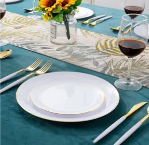 Elegante weiße Einweg-Kunststoffteller mit Goldrand und goldenem Besteck auf Tisch.