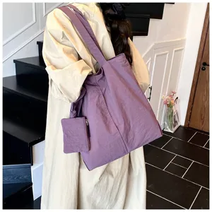 Détail d'un grand sac cabas violet avec une petite pochette assortie sur un trench