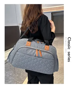 Détail de grand sac de voyage montrant le tissu gris résistant et des accents de cuir marron.