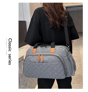 Grand sac de voyage gris en tissu résistant avec poche avant et bandoulière pratique.