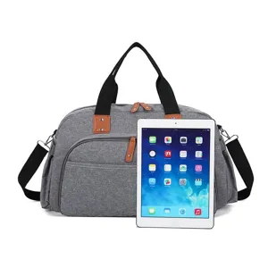 Grand sac de voyage gris en toile robuste avec sangles noires et details en cuir marron.