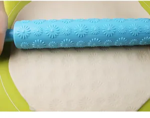 Detail van een blauwe plastic deegroller die mooie madeliefjespatronen in deeg drukt