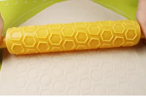 Gedetailleerd overzicht van een gele deegroller die zeshoekige patronen op fondant maakt.