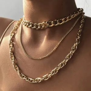 Close-up of a layered punk style gold metal thick chain necklace set on neck