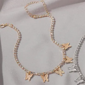 Close-up of sparkling rhinestone butterfly pendants on a gold tennis choker chain.