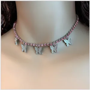 Close-up of silver tennis choker necklace with pink rhinestones and butterfly charms