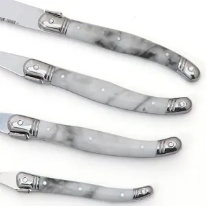 Detail view of stainless steel steak knives with marble pattern handles and metallic bolsters.