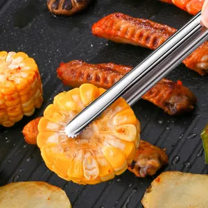 Professional 304 stainless steel BBQ tongs picking up grilled corn on a barbecue pan.
