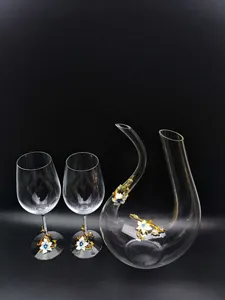 Detailed view of crystal wine decanter and two wine glasses with elegant enamel floral decor.